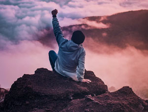 Man on rock against a purple sky